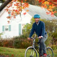Dr. Gersten on a bike in front of fall leaves.