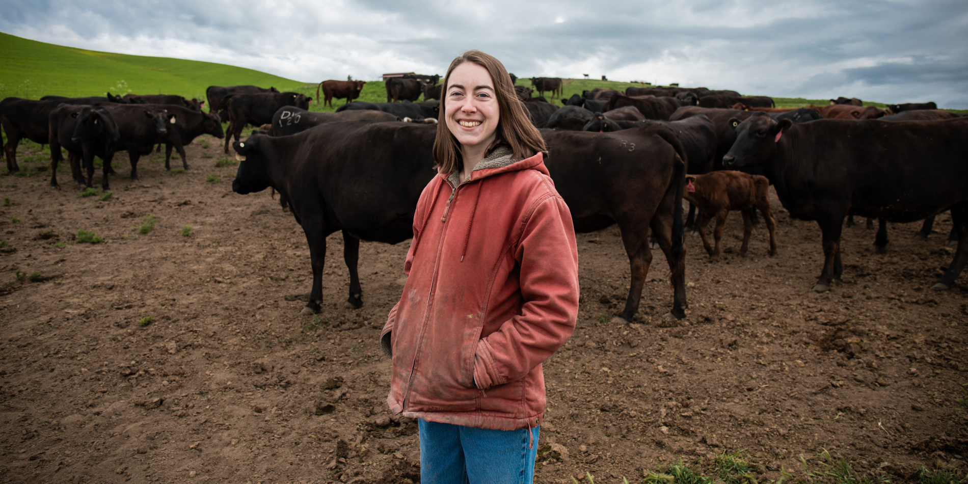 Pearl Griffiths at her family farm with cows in the background.